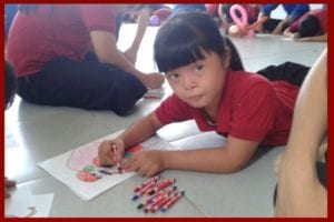 Young girl drawing with an intense look on her face.